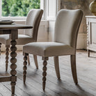 Two upholstered dining chairs with rounded front legs next to a dining table.
