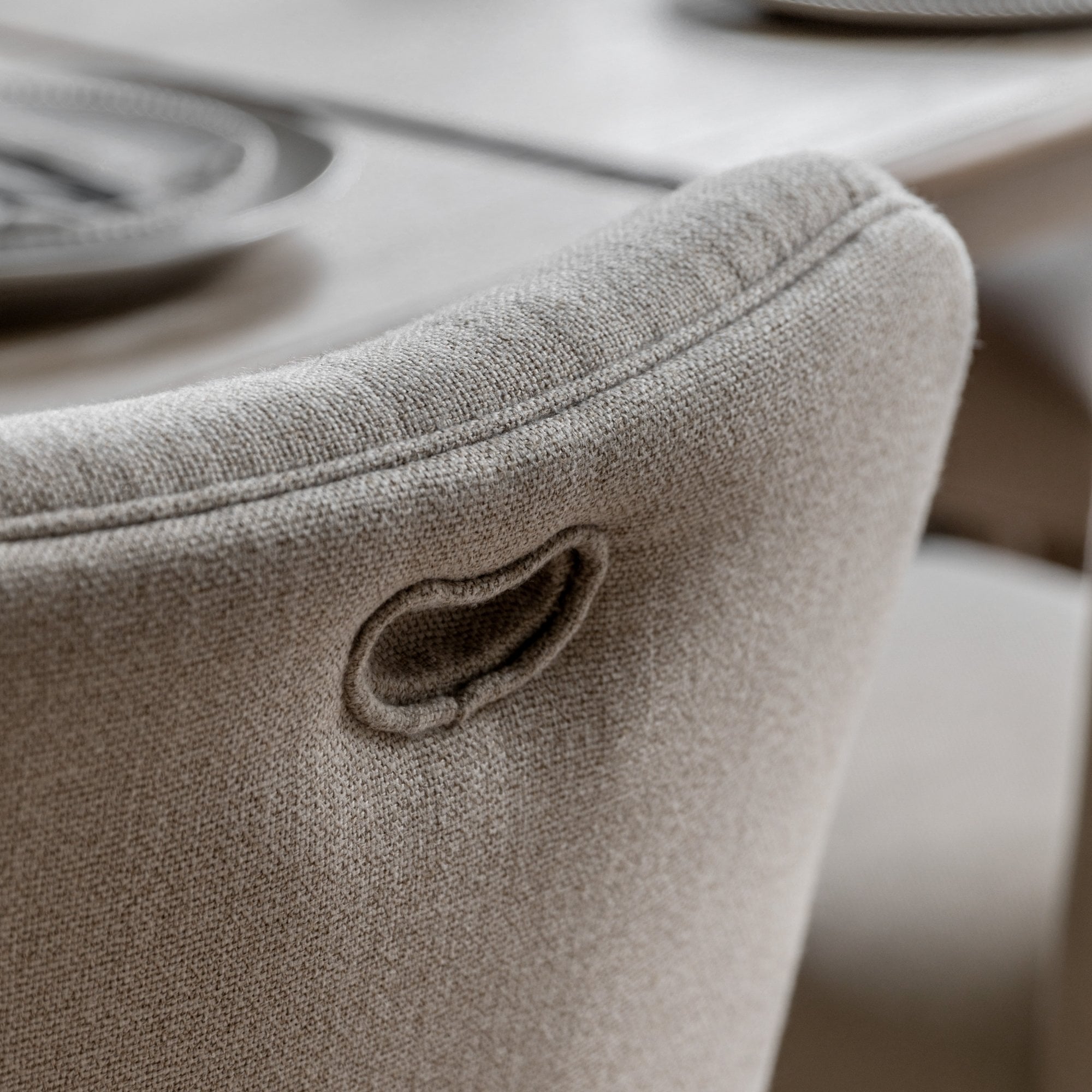 Close-up of the back of an upholstered dining chair with a small handle.