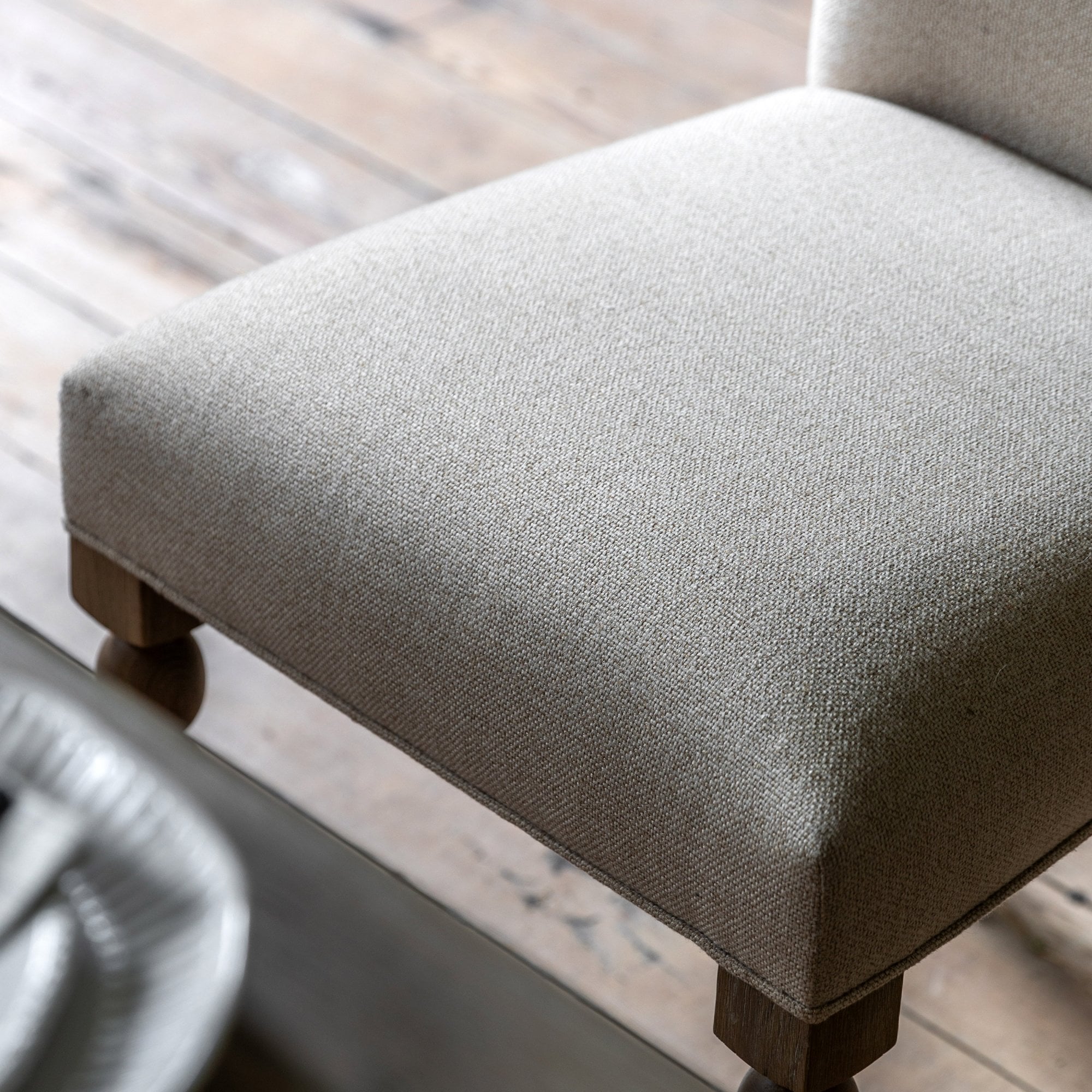 Close-up of the upholstered seat and rounded front legs of a dining chair.