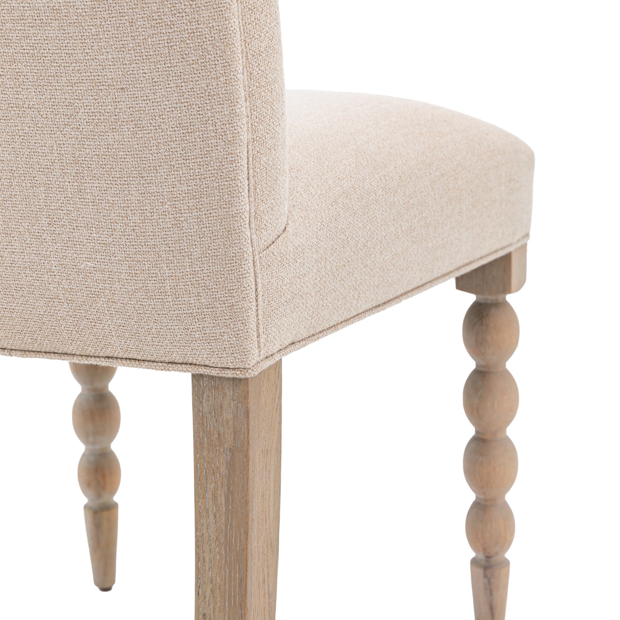 Close-up of the rounded front legs and upholstered seat of a dining chair.