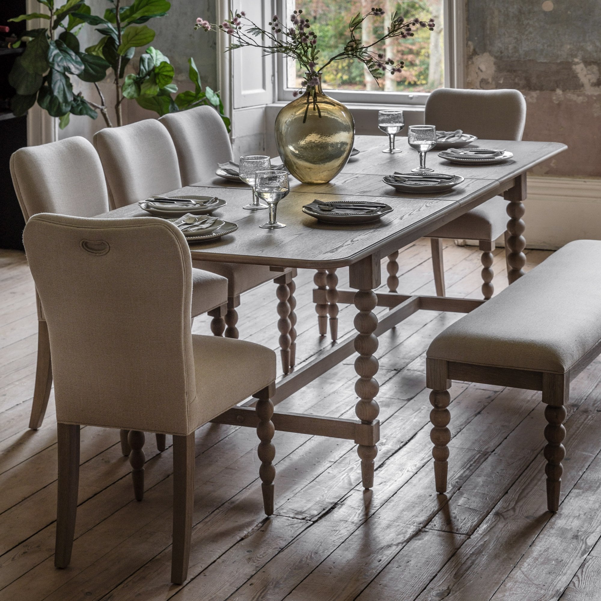 A dining room featuring a wooden dining table with six upholstered chairs and a matching bench.