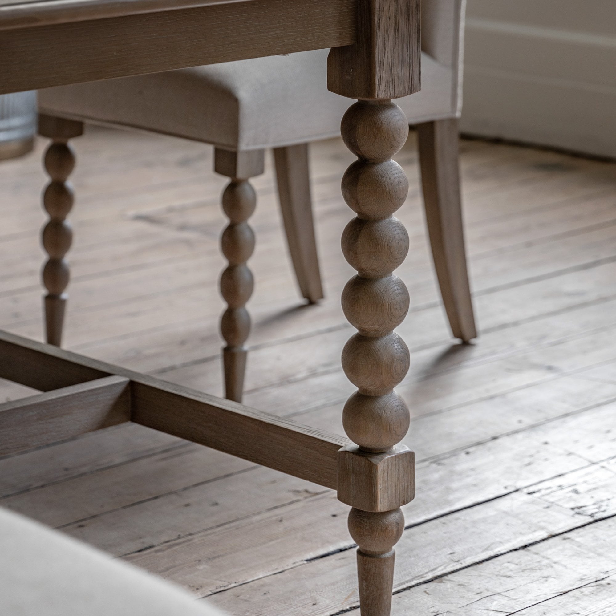 Close-up of the wooden bobbin leg design of a dining table and matching chair leg.