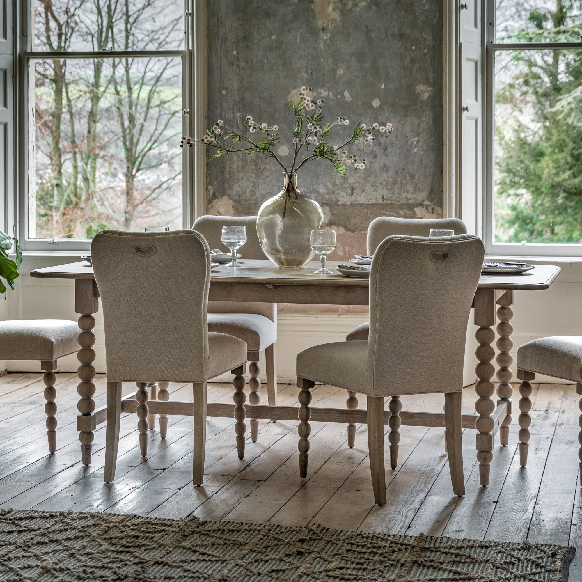 A dining room with a wooden dining table, upholstered chairs, and a window view.