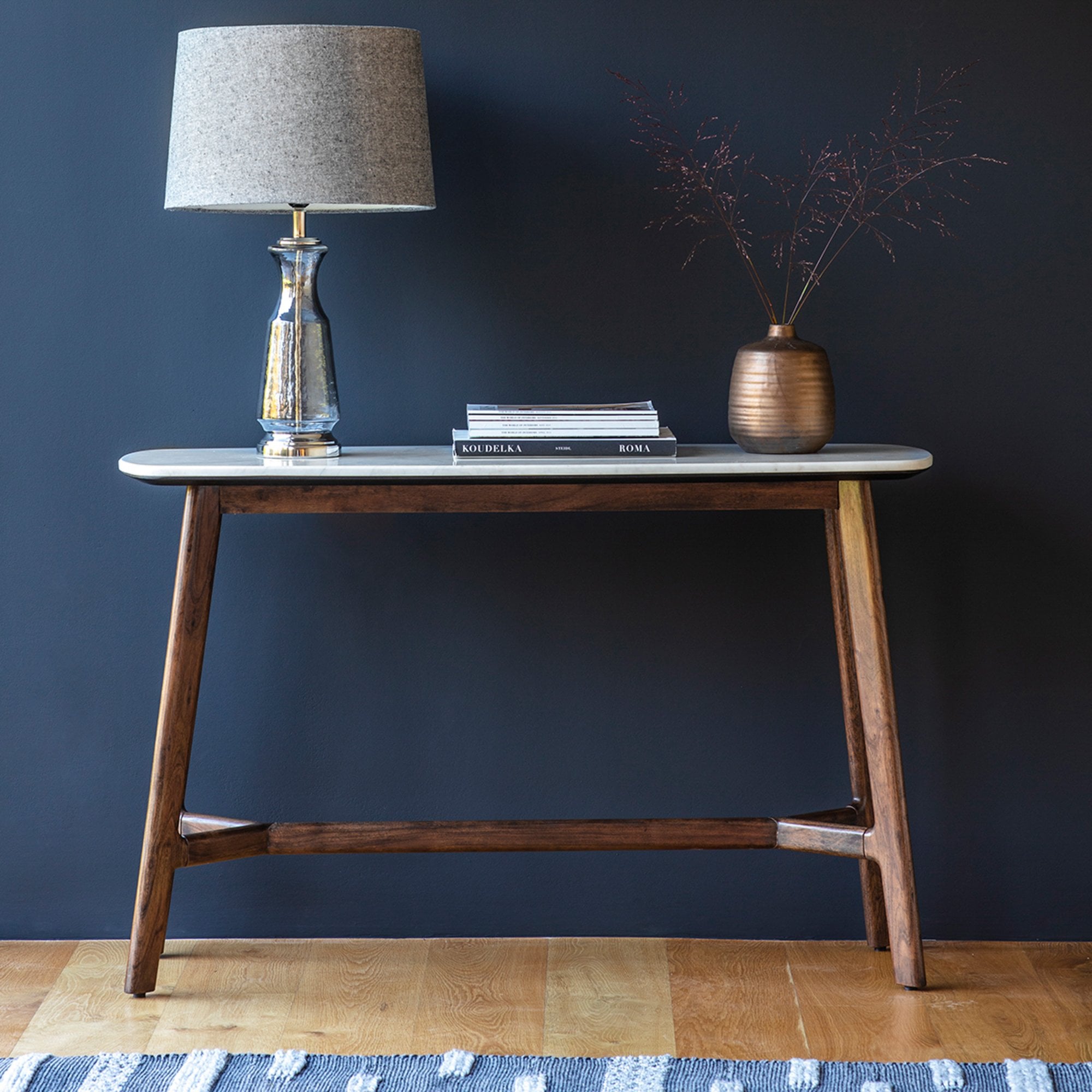A console table with a white marble top and dark wooden legs.