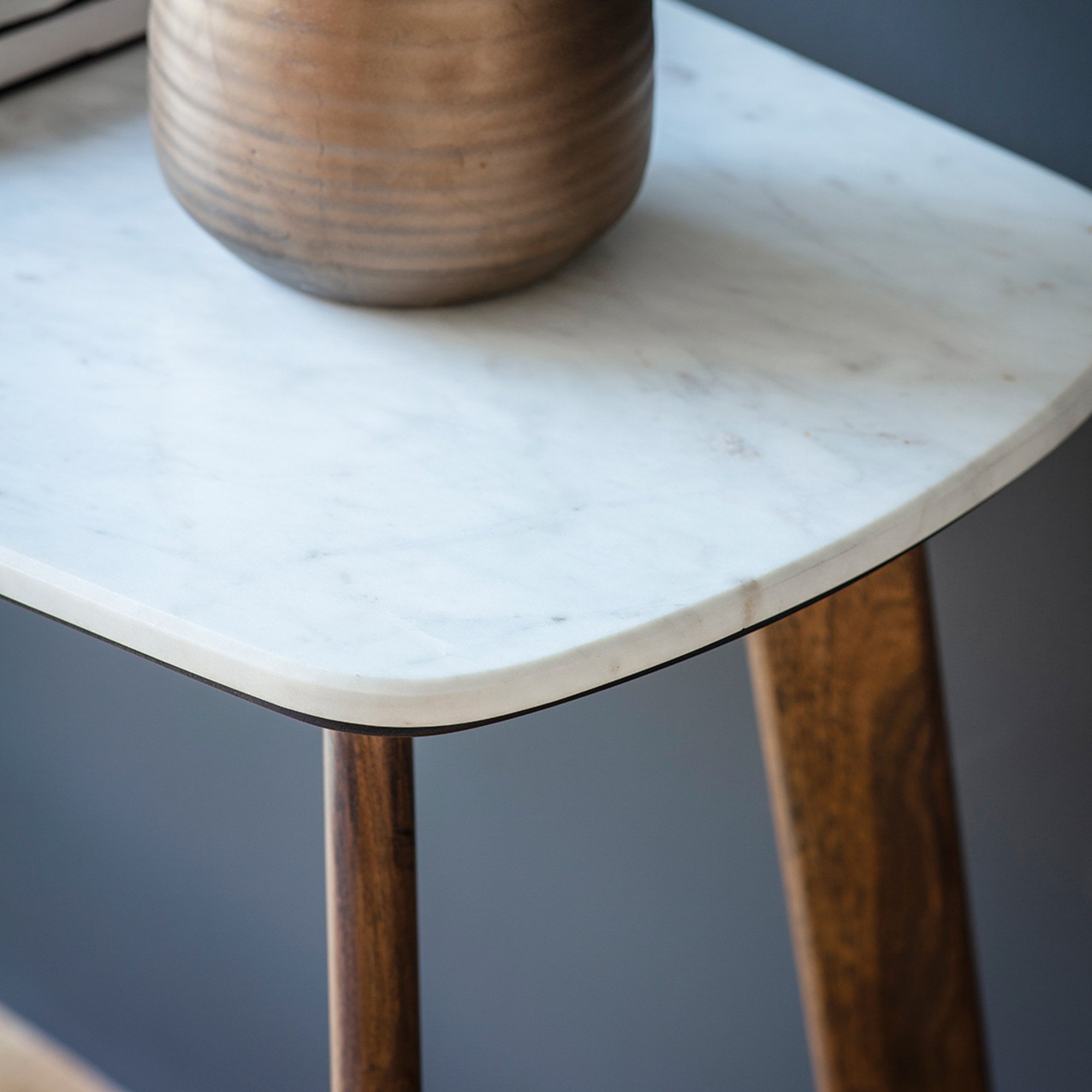 A closeup of the rounded corner of a console table's white marble top.