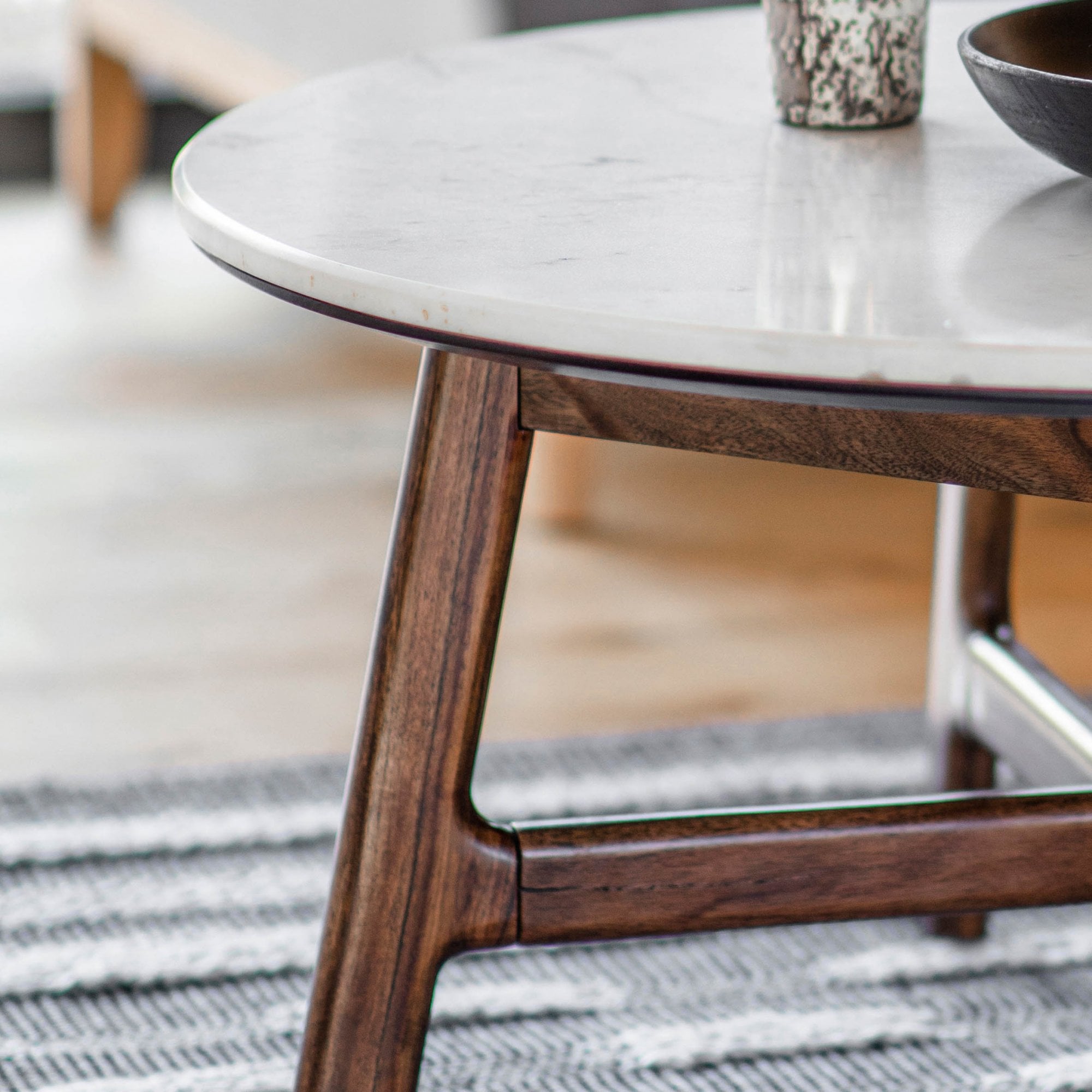 Close-up of the round coffee table's white marble top and dark wood legs.