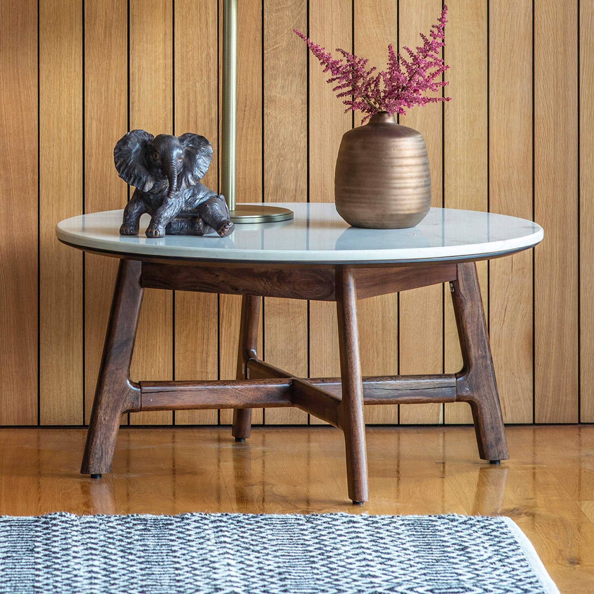 Round coffee table with a white marble top and dark wood legs, styled with decor.