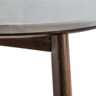 Detail of the connection point between the white marble tabletop and wooden leg.