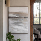 Abstract painting in neutral tones hanging on a wall in a living room.