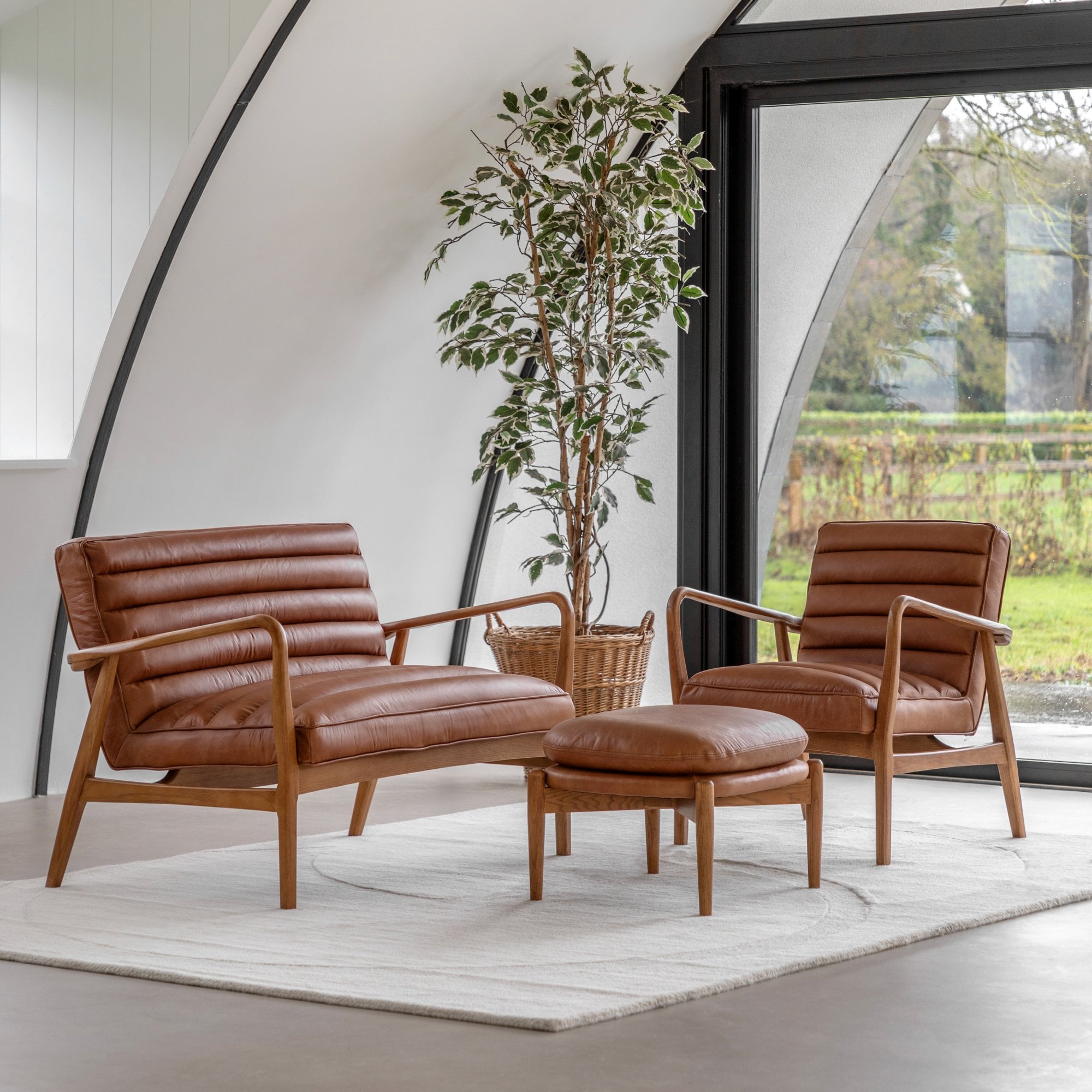 Complete living room set with two tan leather armchairs and a matching ottoman.