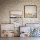 Collection of abstract paintings on a white brick wall.