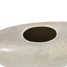 A close up of the opening of a light grey, stone-like decorative vase, showing its texture.