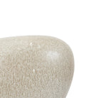 A close up of the curved, stone-like texture of a light grey decorative vase.