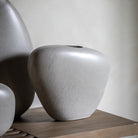 A close up of the curved, stone-like texture of a light grey decorative vase.