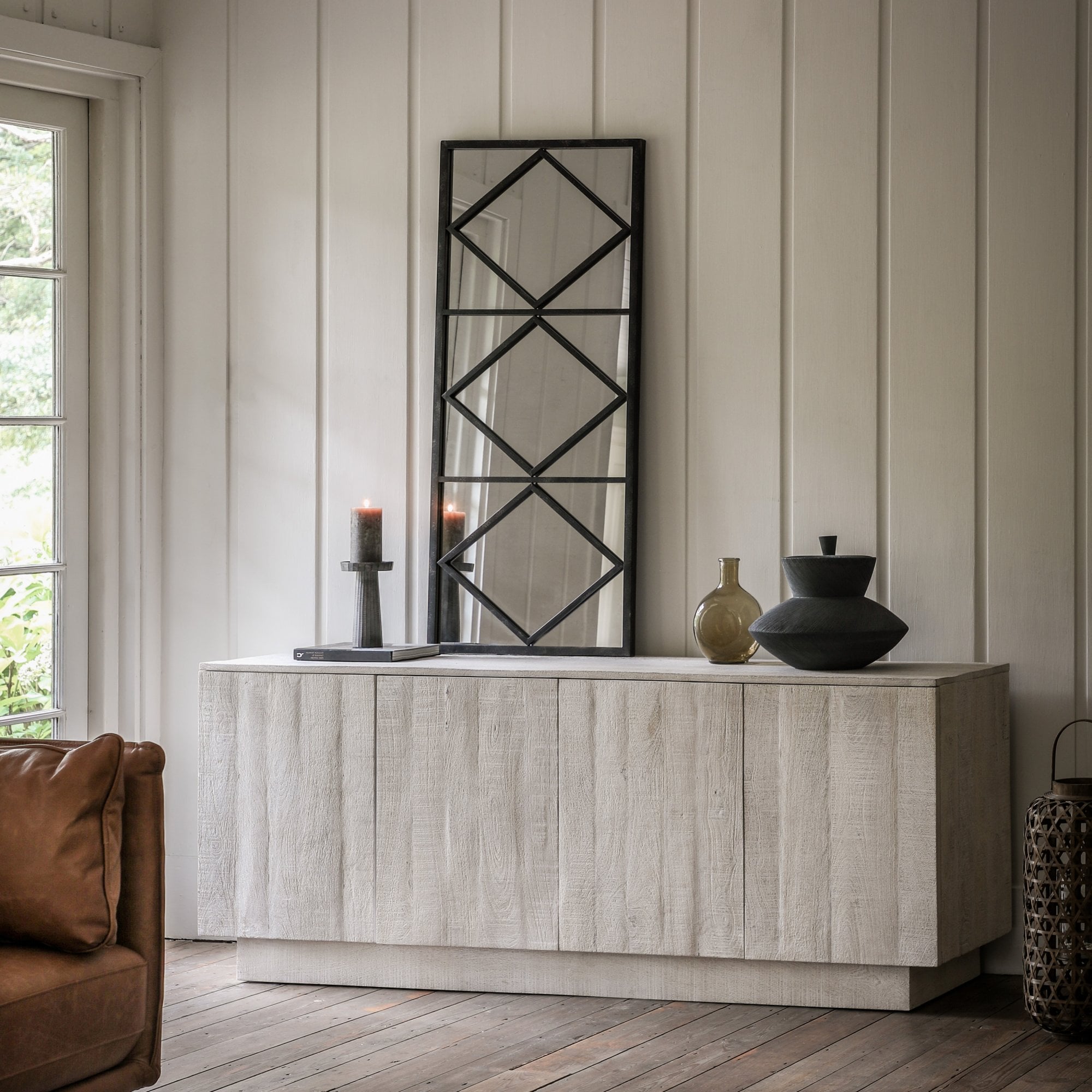 A modern sideboard in a living room, featuring a geometric mirror and decorative vases.