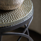 Close-up of the hammered metal top and black metal geometric base of a round side table.