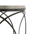 Close-up of the hammered metal top and black metal geometric base of a round side table.