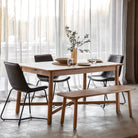 Light wood dining table set with black chairs and a matching bench.