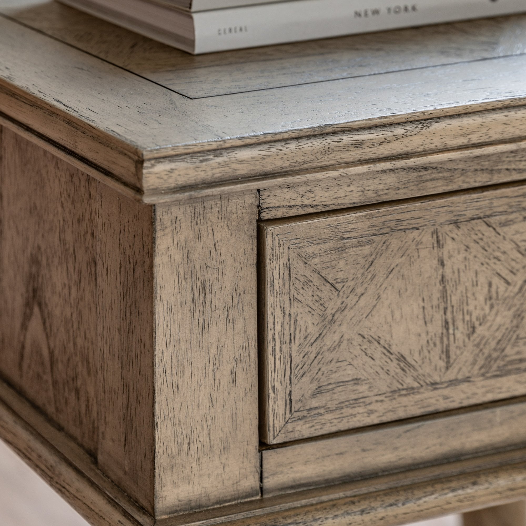Close-up of the distressed grey drawer with carved geometric details and a round knob.