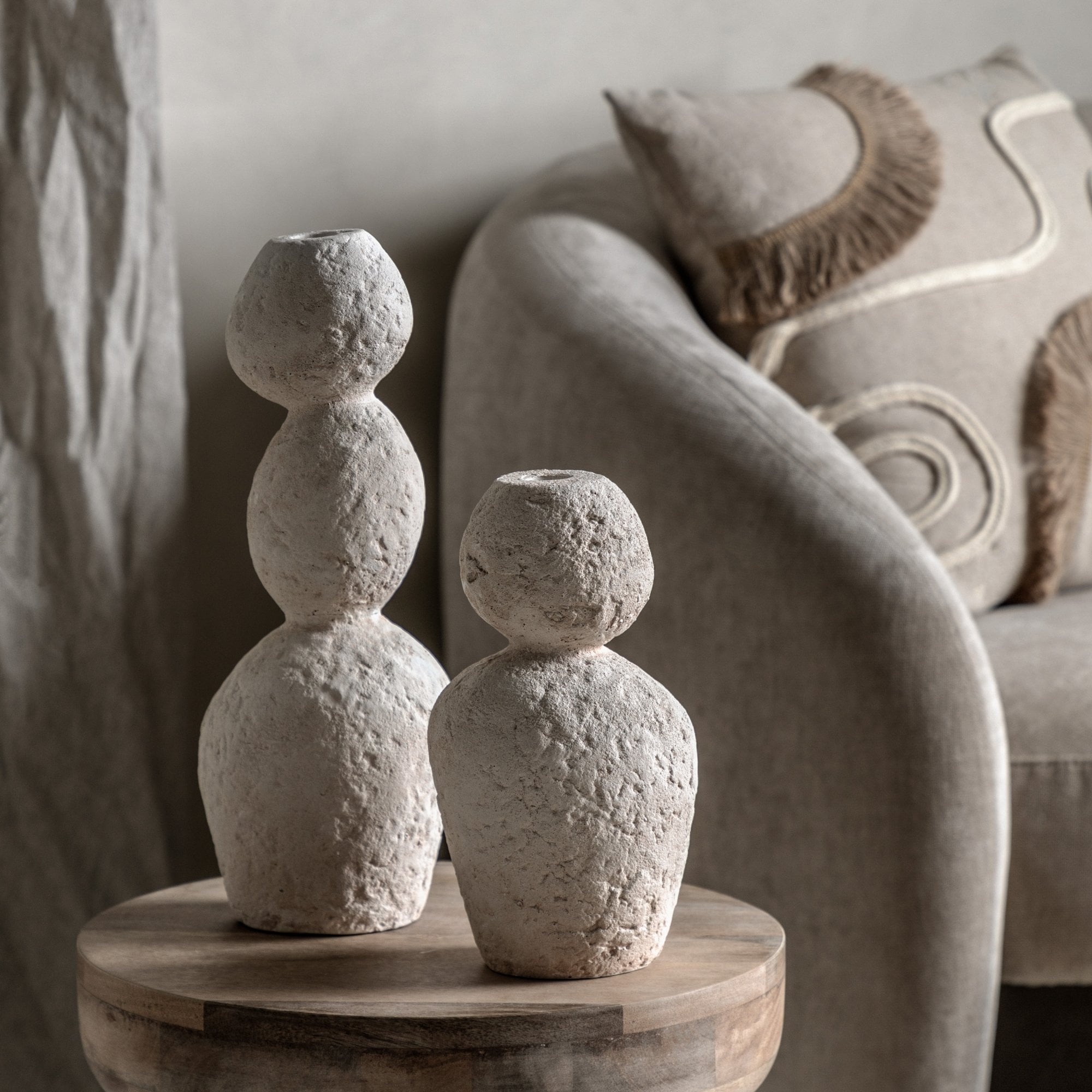 Two textured white vases of different heights on a wooden table.