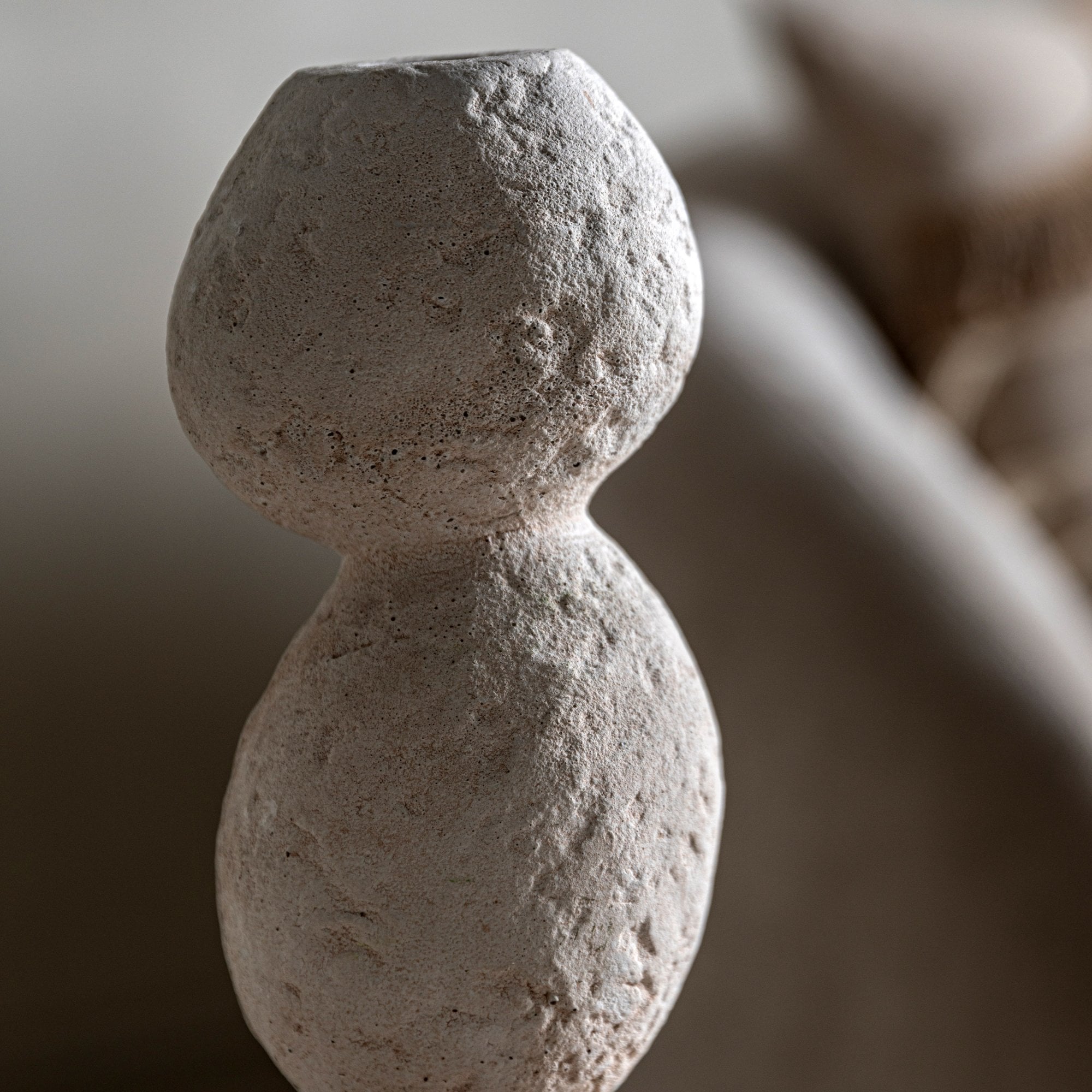 A close-up of a textured white stacked stone vase.