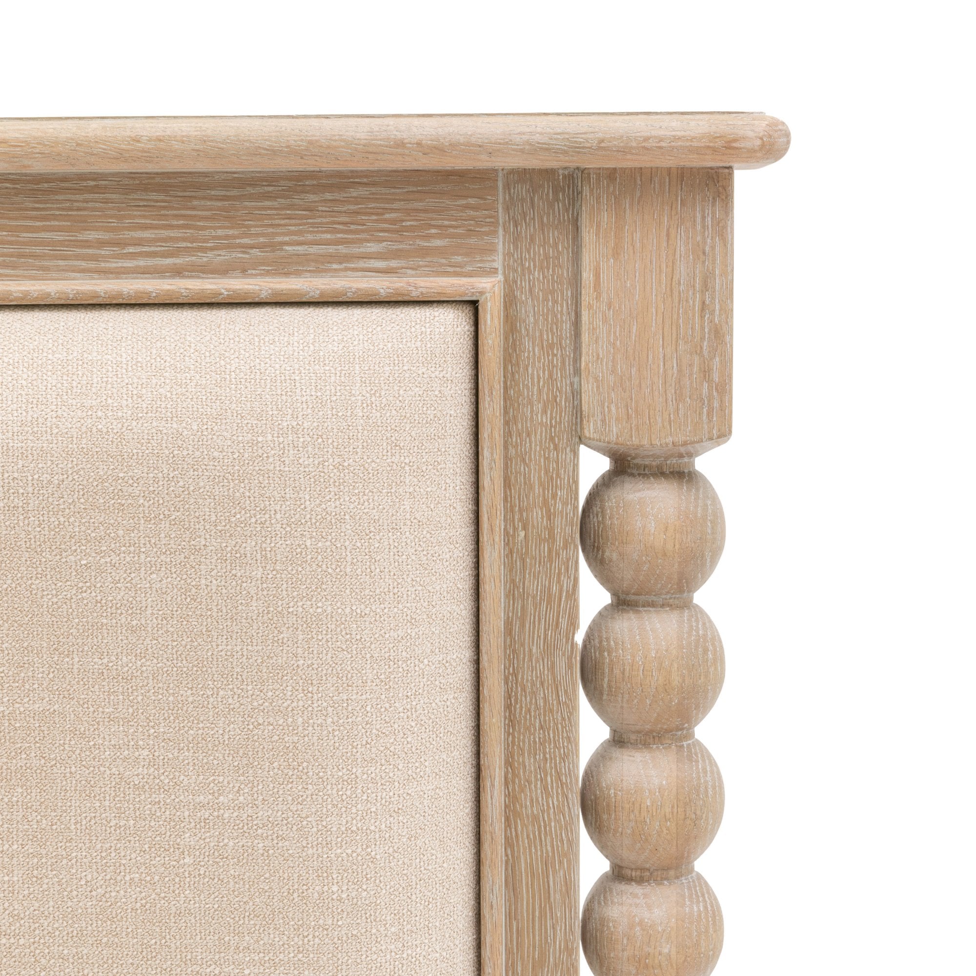 A close-up of the upholstered headboard and carved wood detailing of the bed frame.