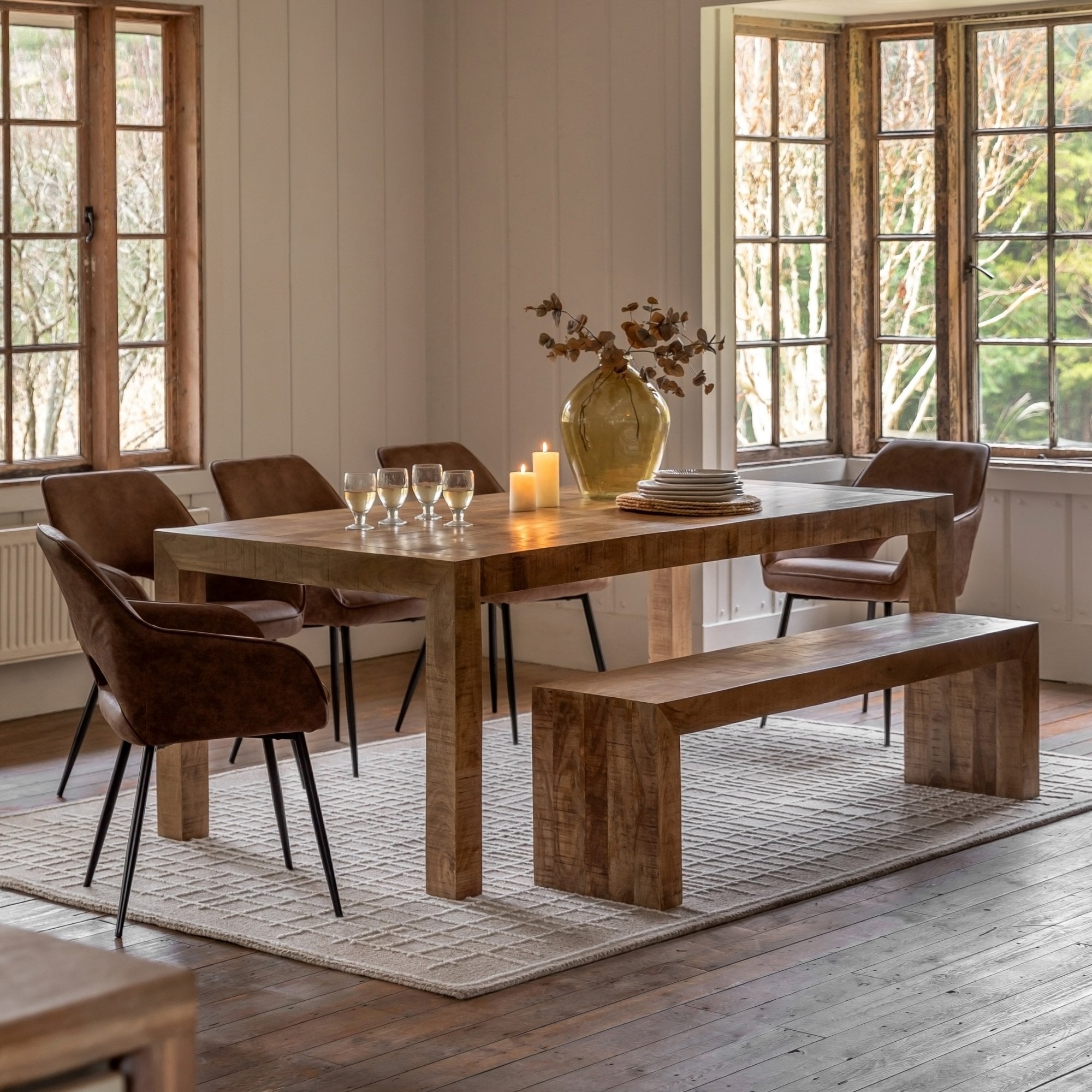 A full view of a rustic dining room with a wooden table, chairs, and a matching bench.