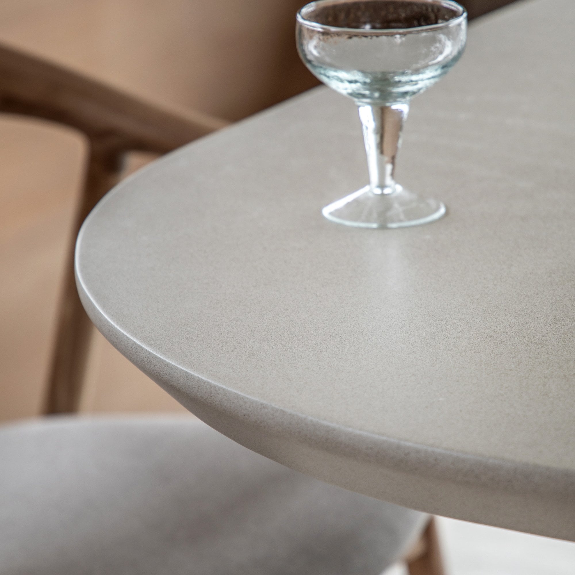 Close-up of the smooth, light-colored tabletop with a glass goblet.