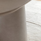 Detailed view of the table's sturdy, conical pedestal base on a textured rug.