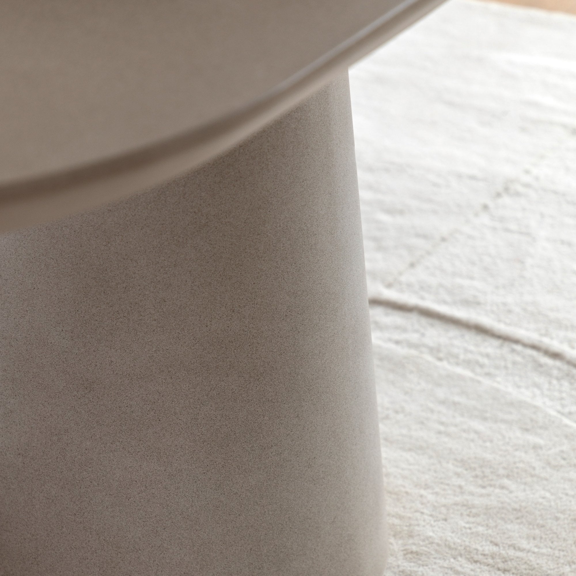 Detailed view of the table's sturdy, conical pedestal base on a textured rug.