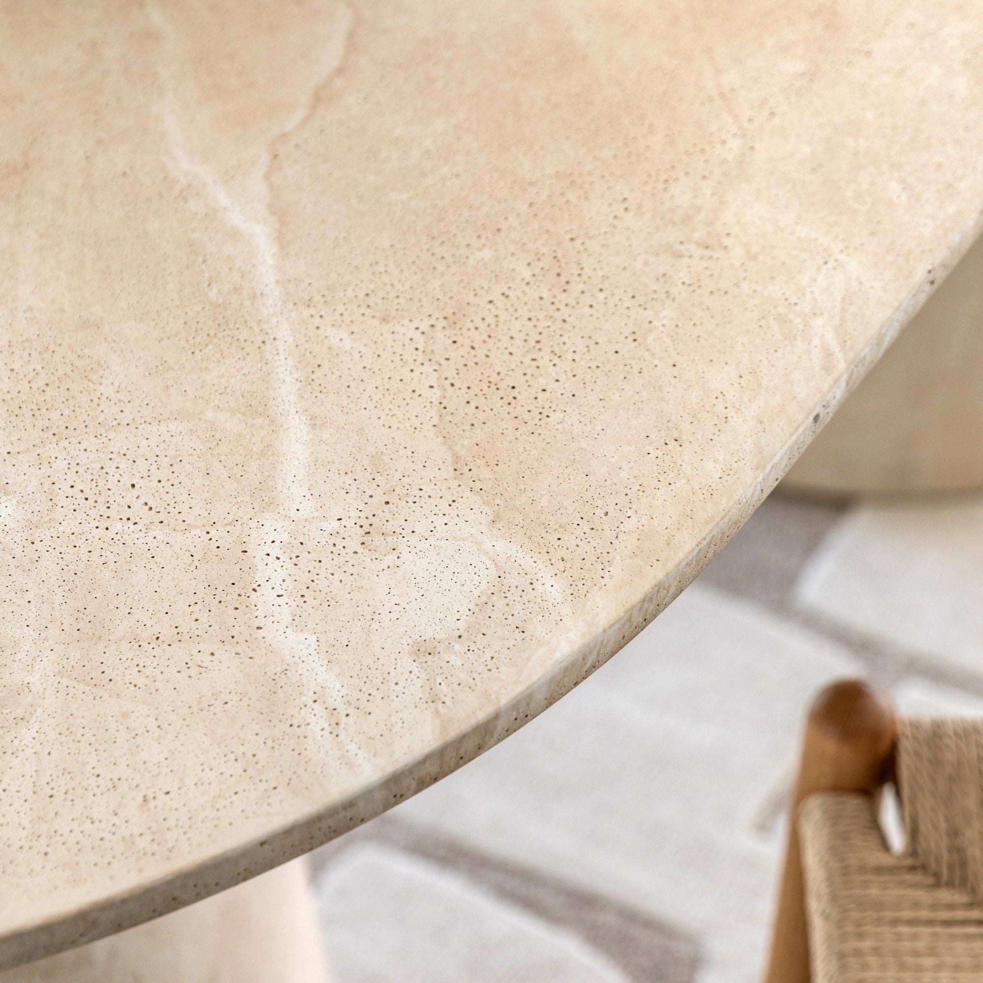 Close-up of the light beige stone tabletop, showing its textured surface and natural veining.