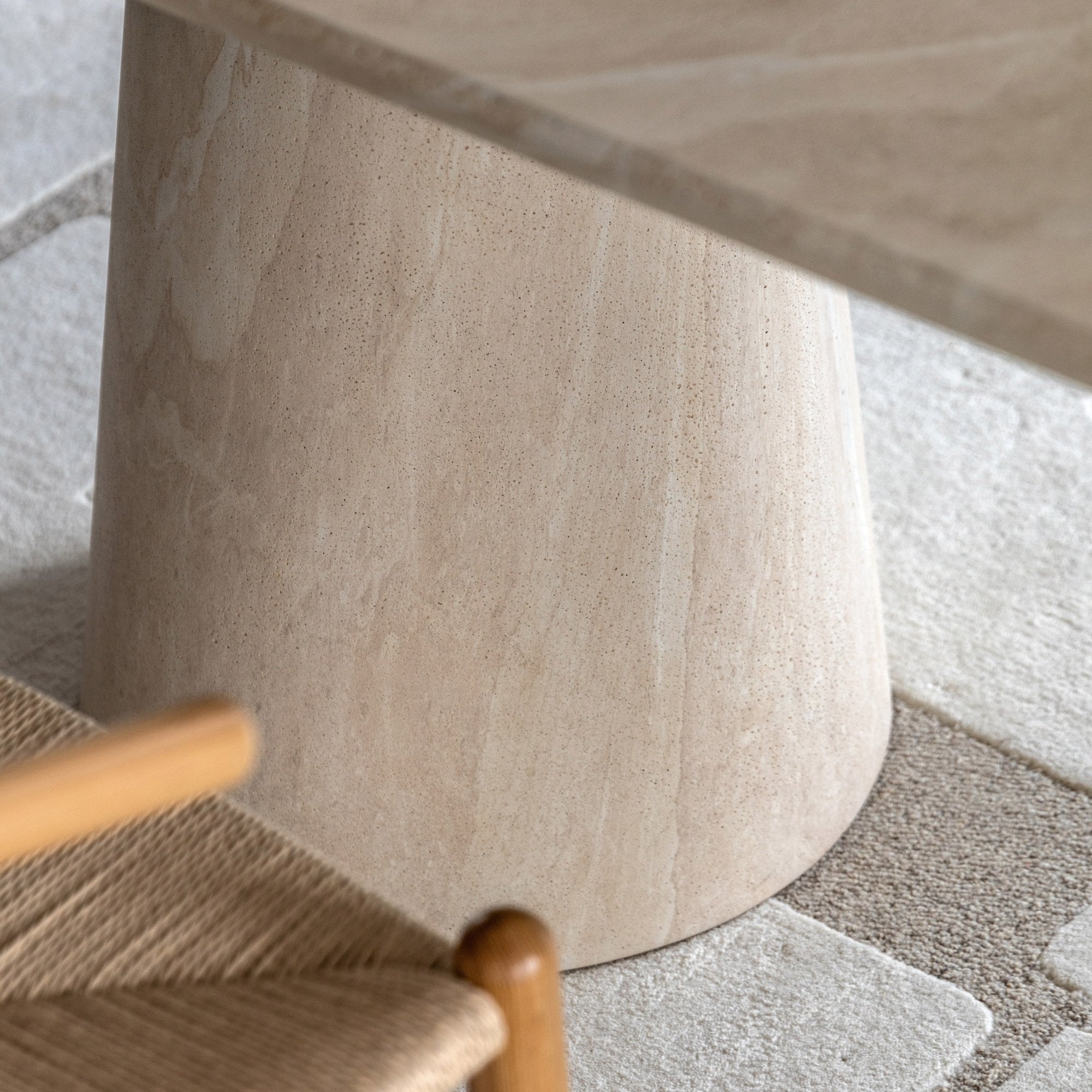 Close-up of the light beige stone table base, showcasing its conical shape and smooth finish.