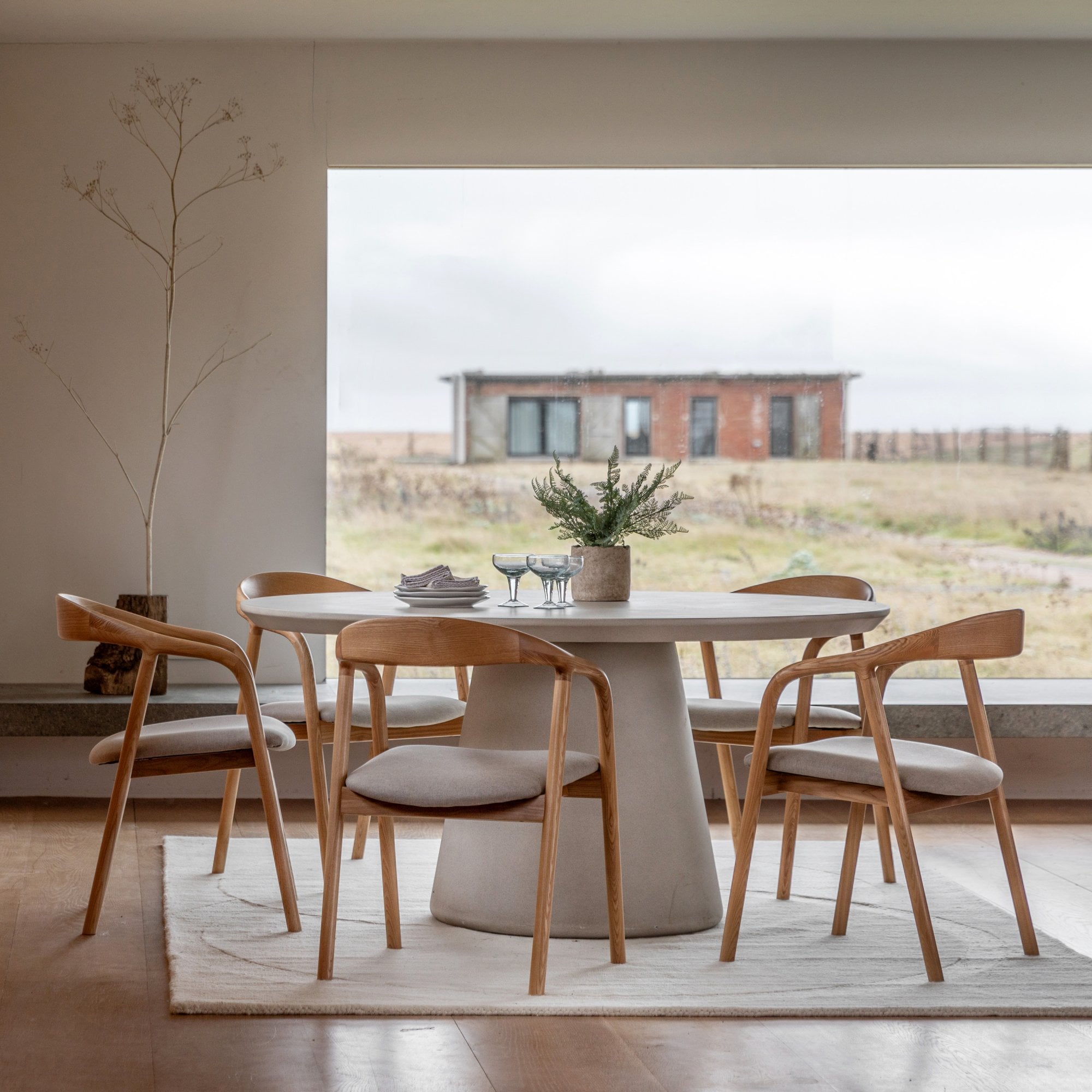 Dining room with a round dining table surrounded by five wooden dining chairs.