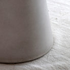 Close-up of the textured base of a light grey dining table on a white rug.