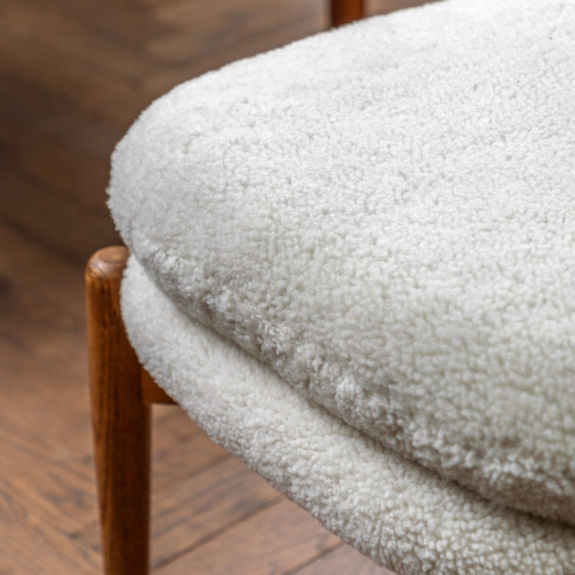 Close-up of the textured white sheepskin upholstery of a footstool.