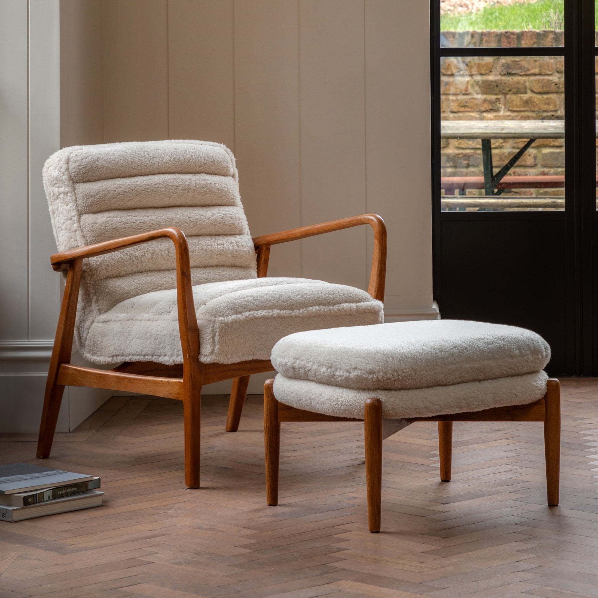 A white sheepskin armchair and matching footstool with light wooden frames in a living room.