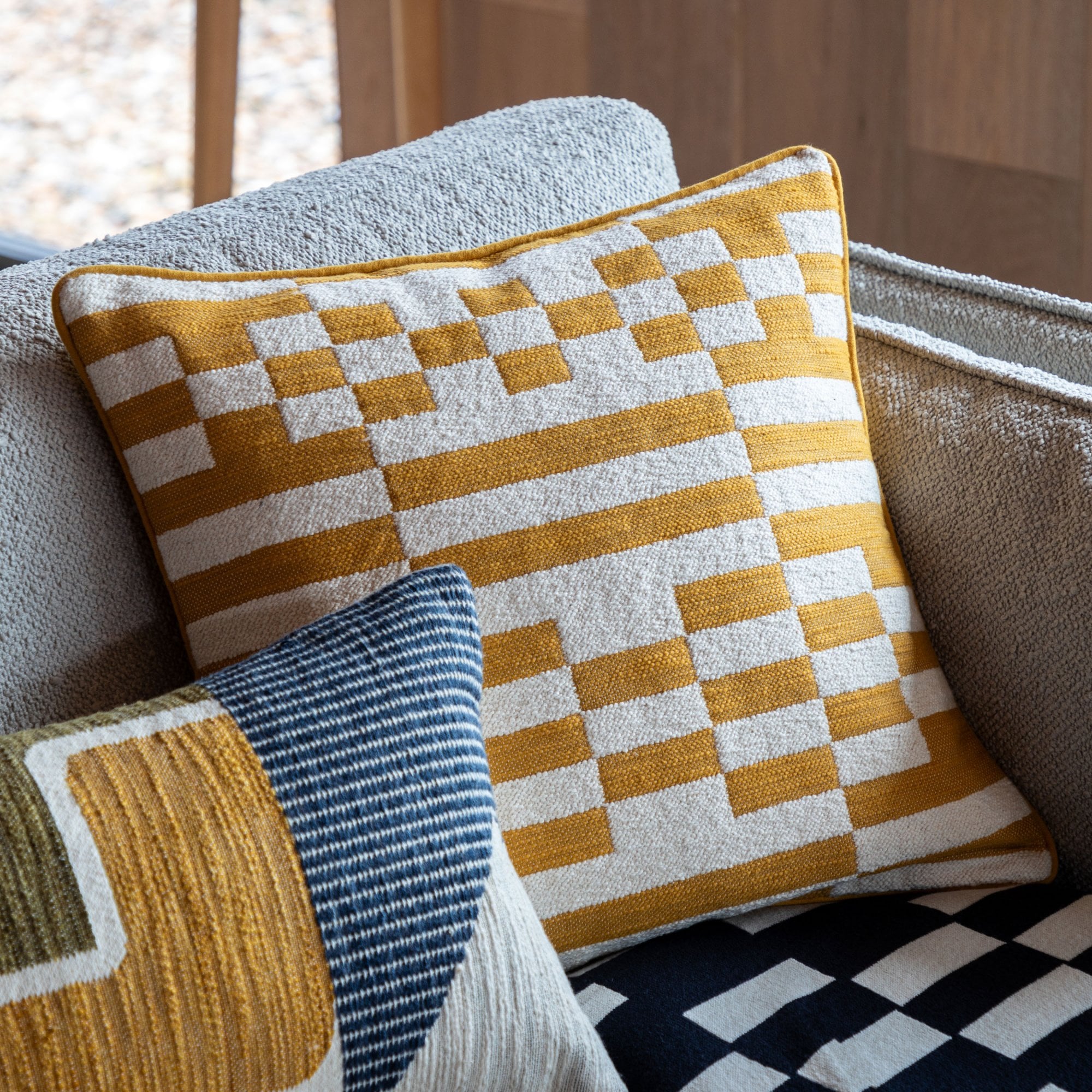 Close-up of a decorative pillow with a yellow and white geometric pattern on a couch.