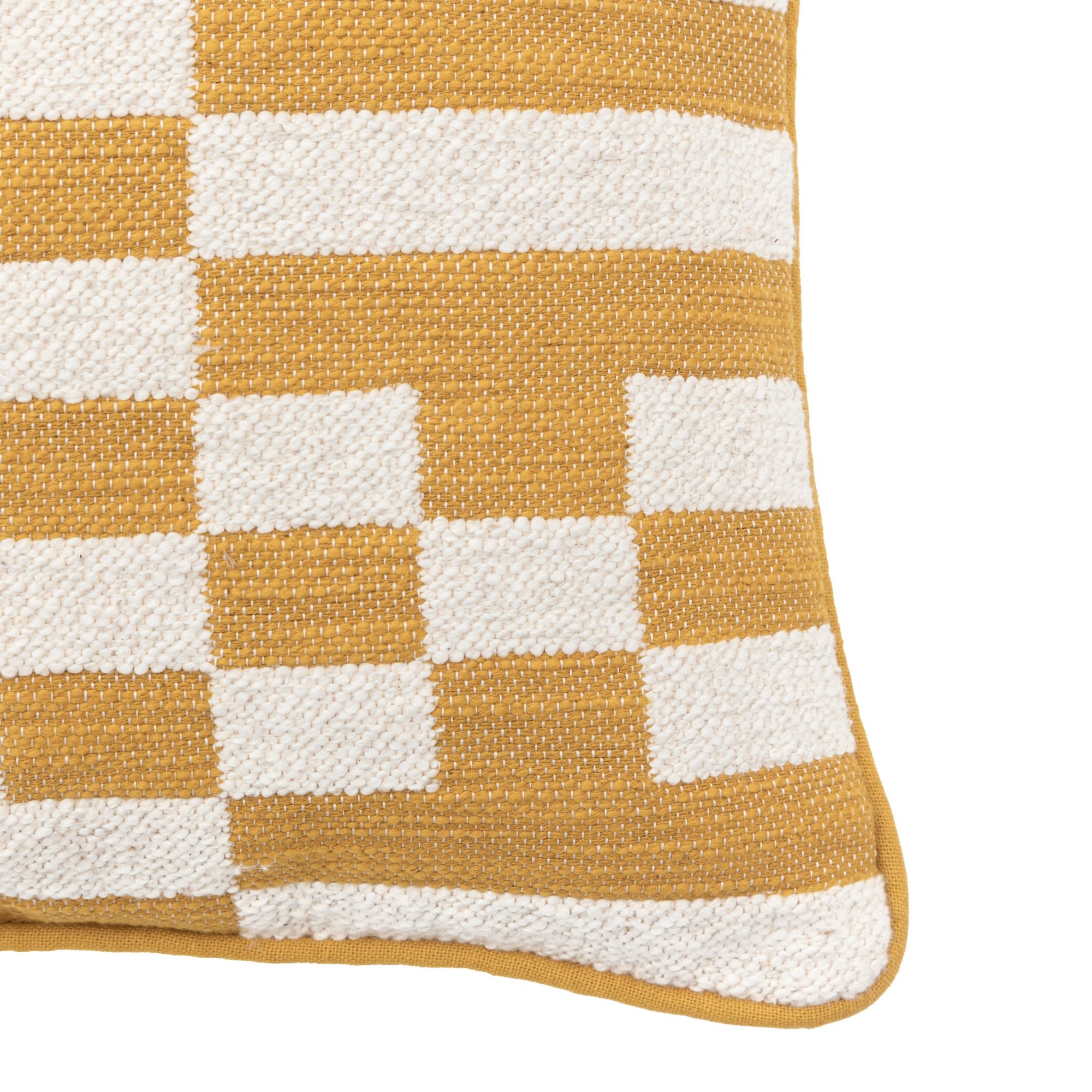 Close-up of the corner of a yellow and white geometric pattern pillow.