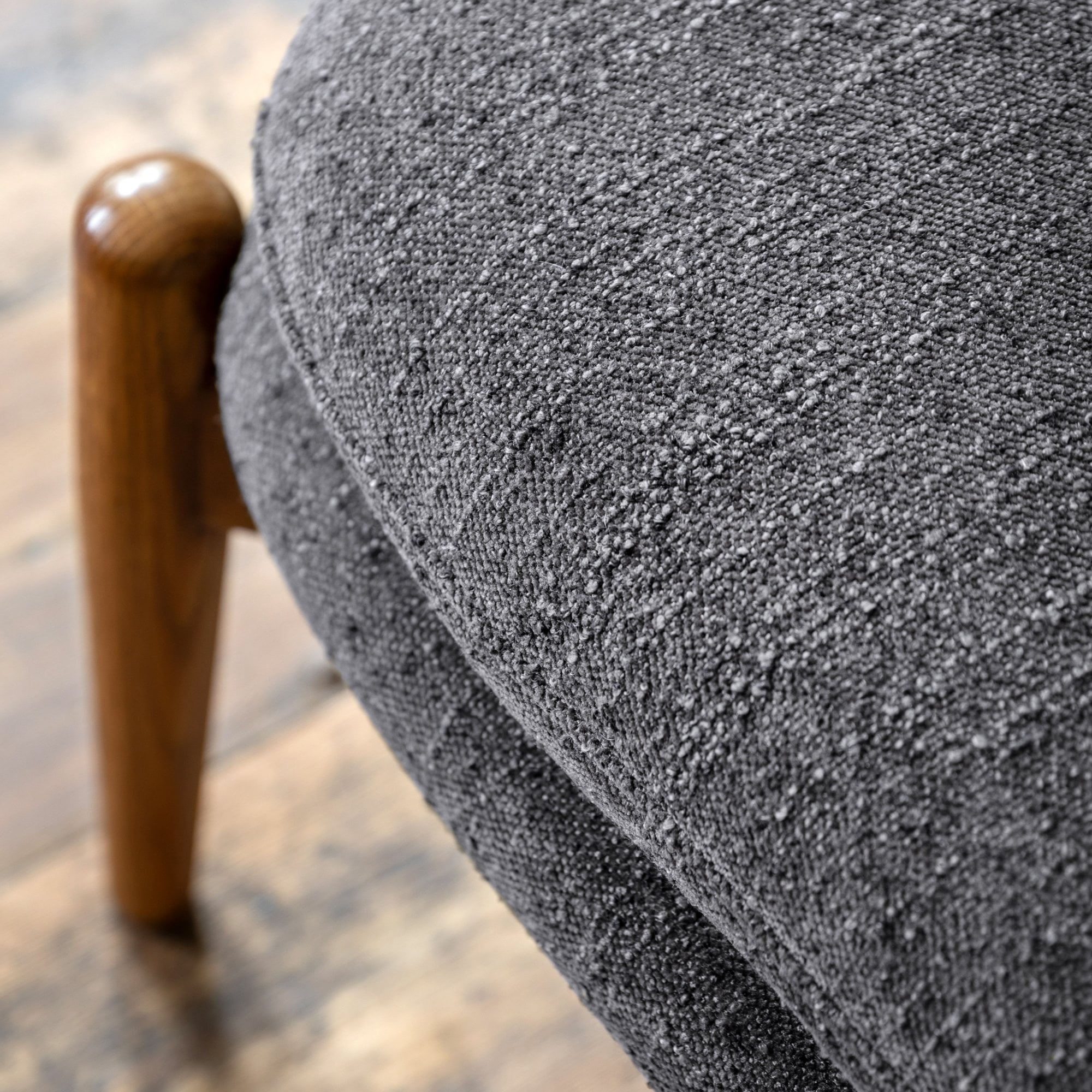 Detailed view of the textured grey fabric upholstery on an ottoman cushion.