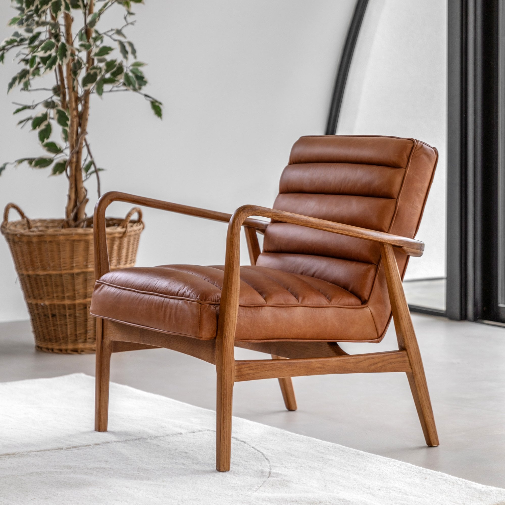 Brown leather armchair with a plant in a basket in the background.