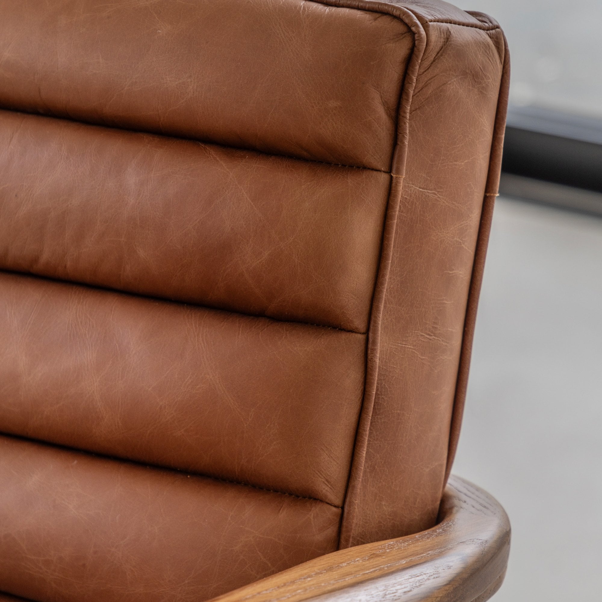 Close-up of the textured brown leather upholstery of an armchair.