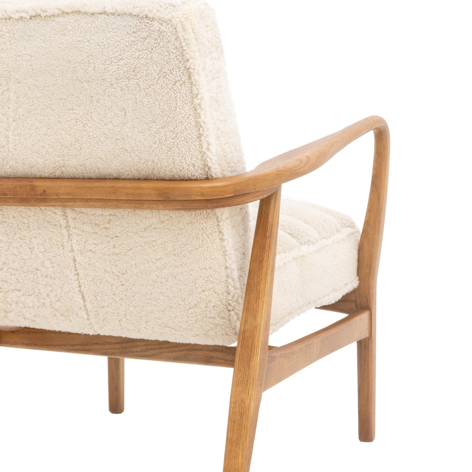 Close-up of the back and side of a cream-colored armchair's wood frame and upholstery.