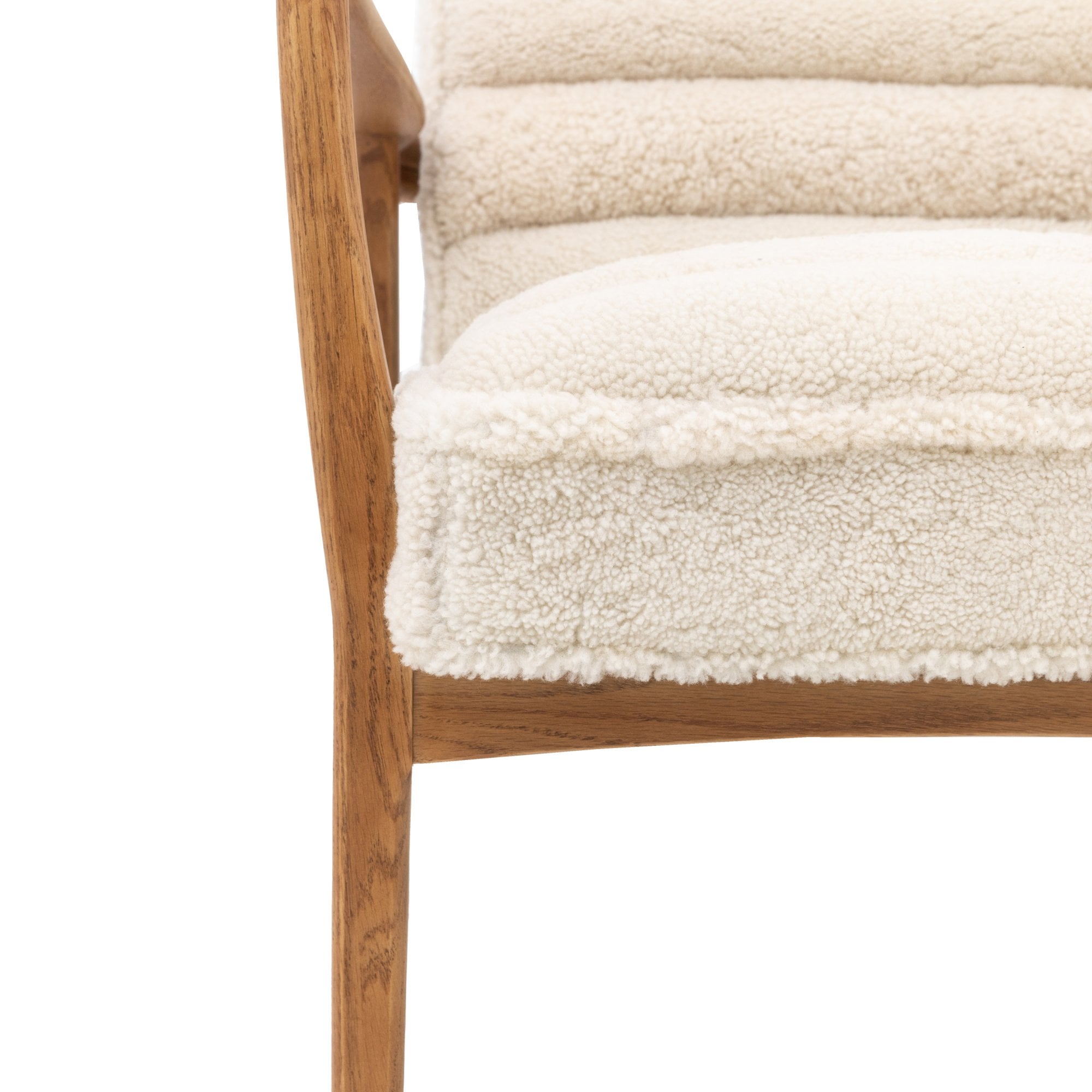 Detailed view of the textured cream fabric and wooden leg of the armchair.
