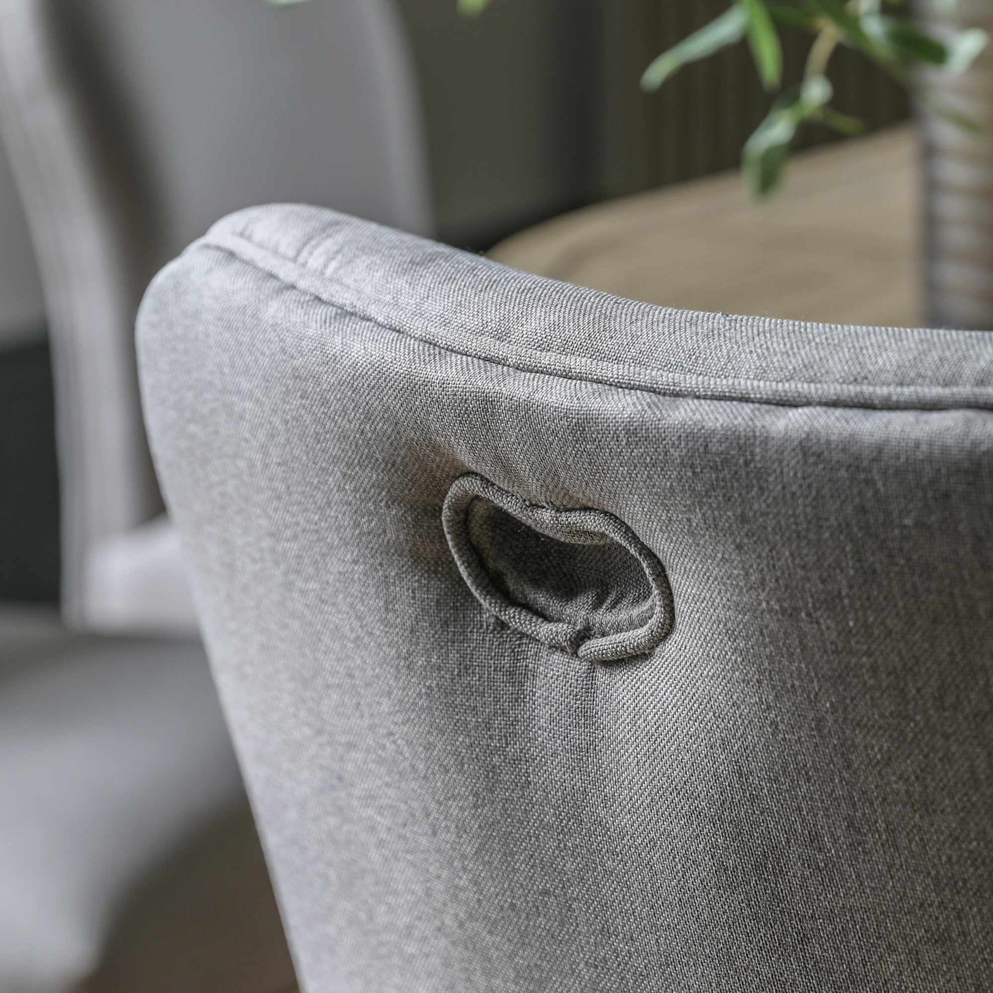 Close-up of the grey fabric upholstered chair's back with a handle cut-out detail.