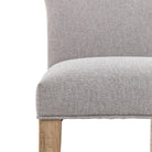 Close-up of the grey fabric upholstered seat and light wooden leg of the dining chair.