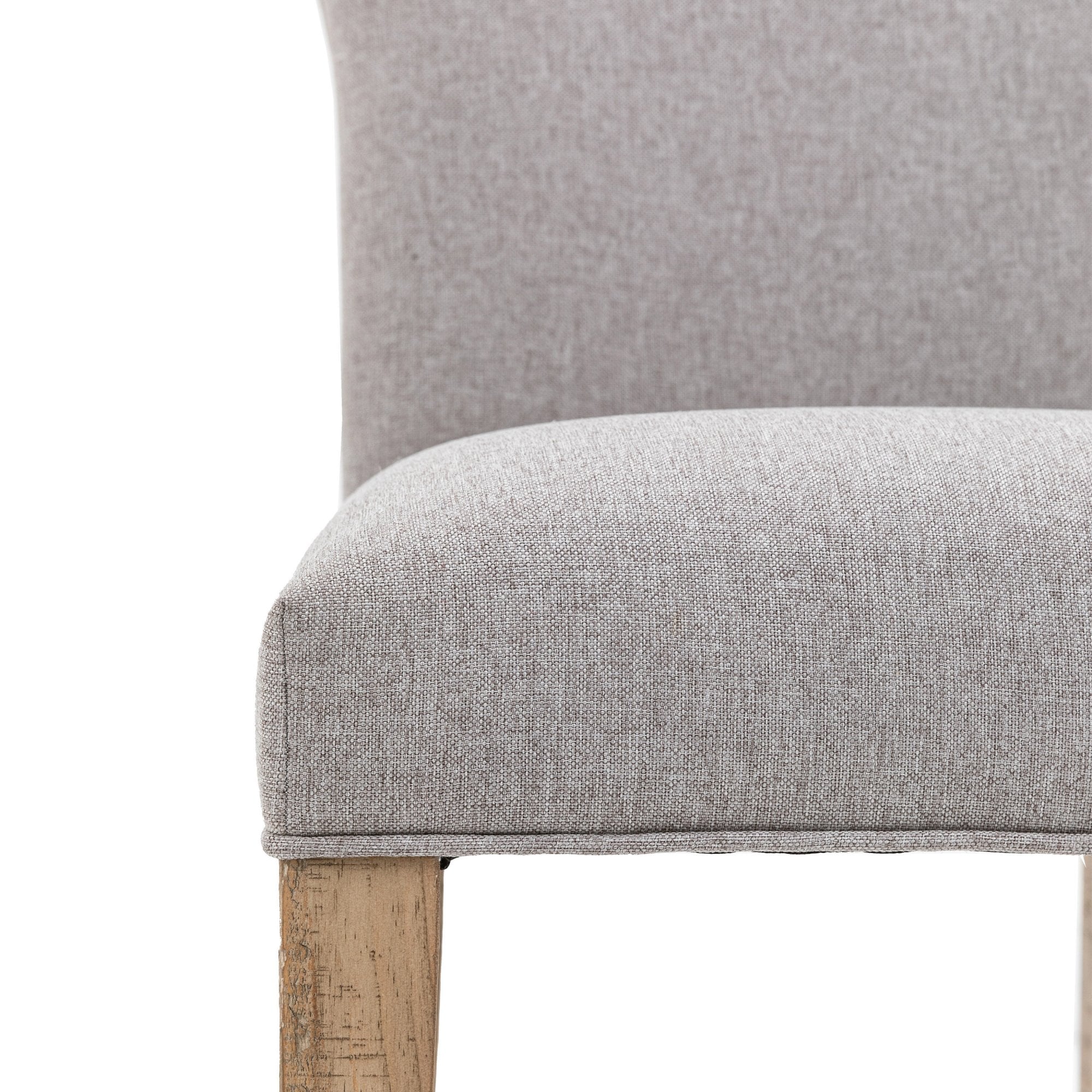 Close-up of the grey fabric upholstered seat and light wooden leg of the dining chair.