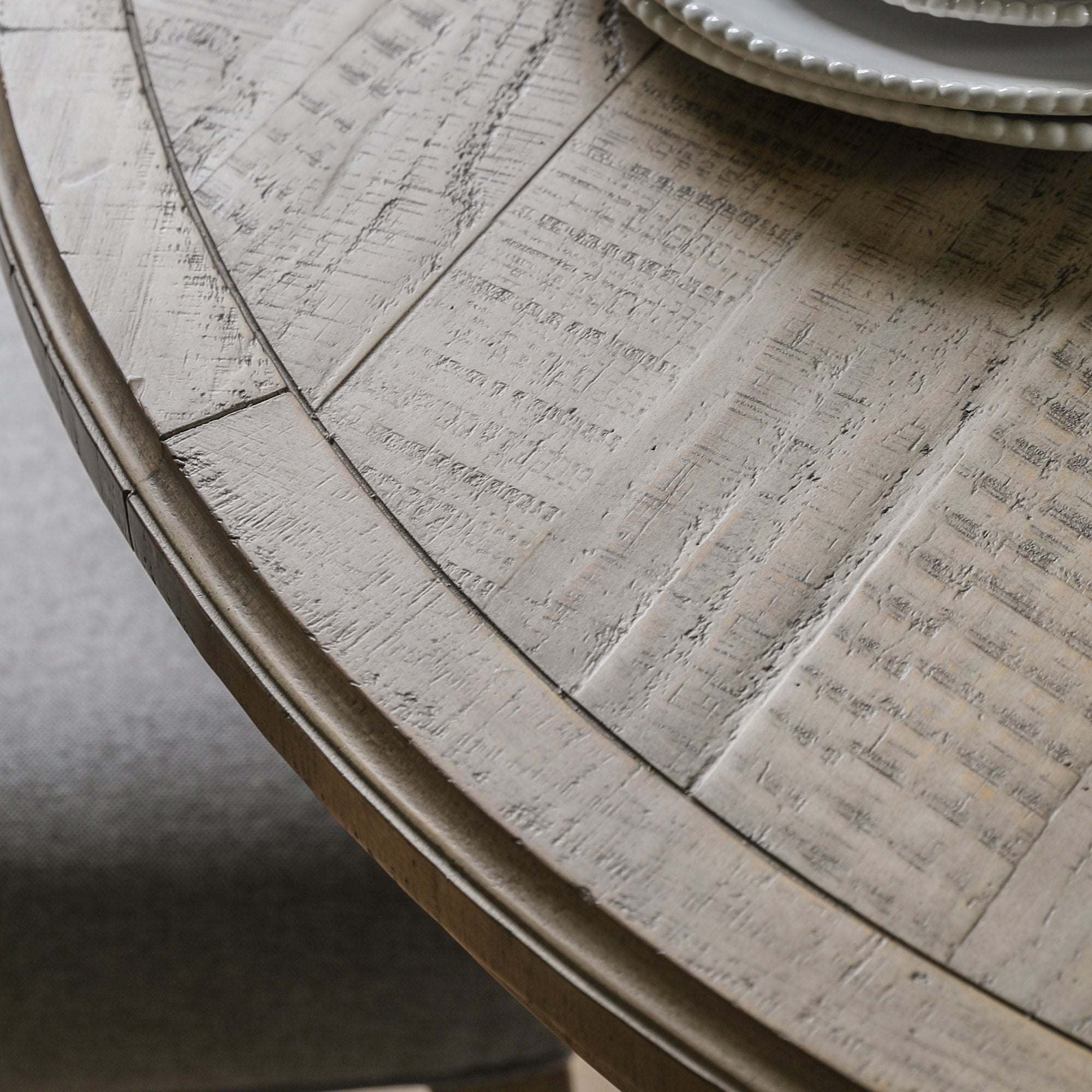 Close-up of the distressed, round wooden tabletop with visible grain.