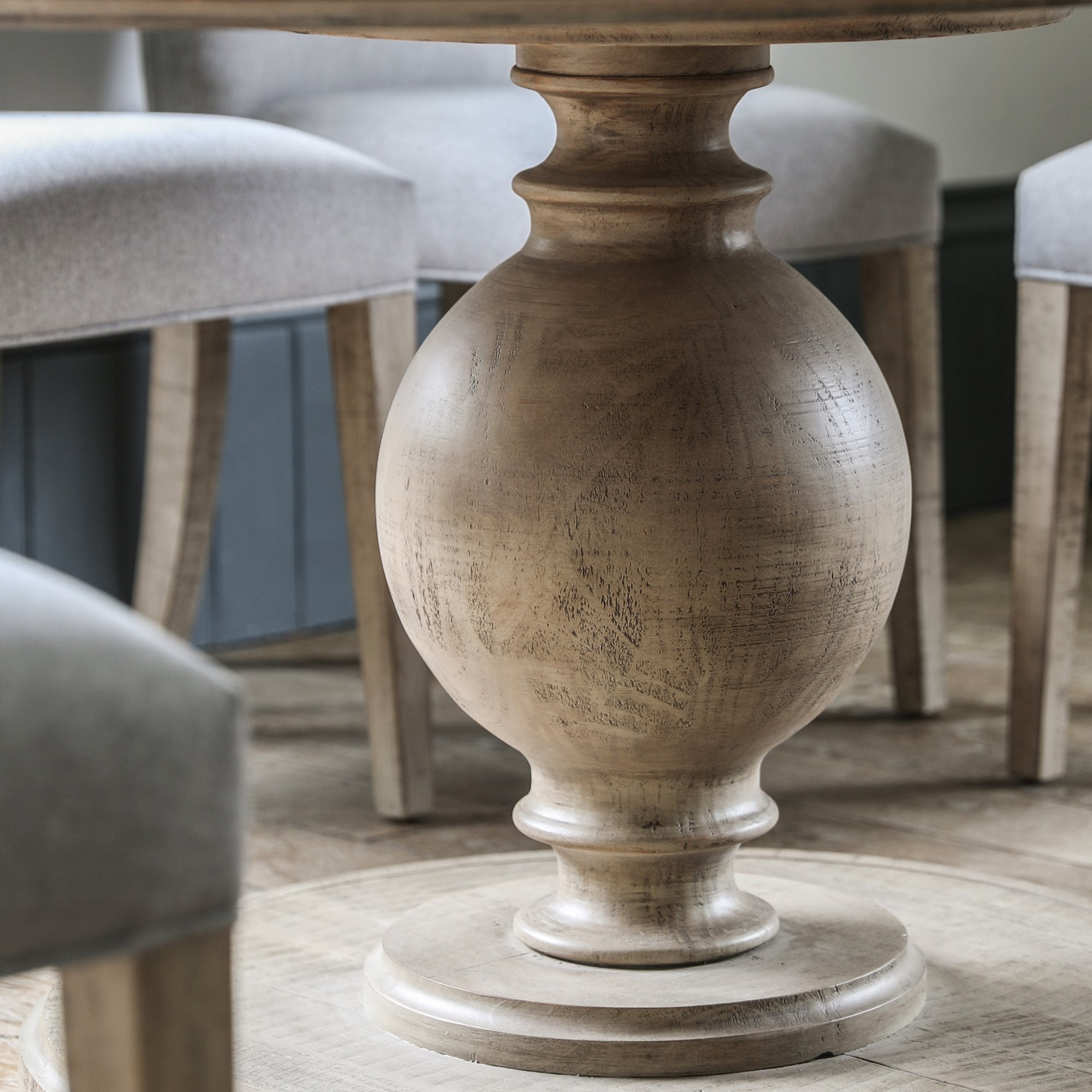 Close-up of the turned wooden pedestal base of the dining table.