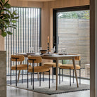 A modern dining room with a long wooden table and four mustard yellow chairs.