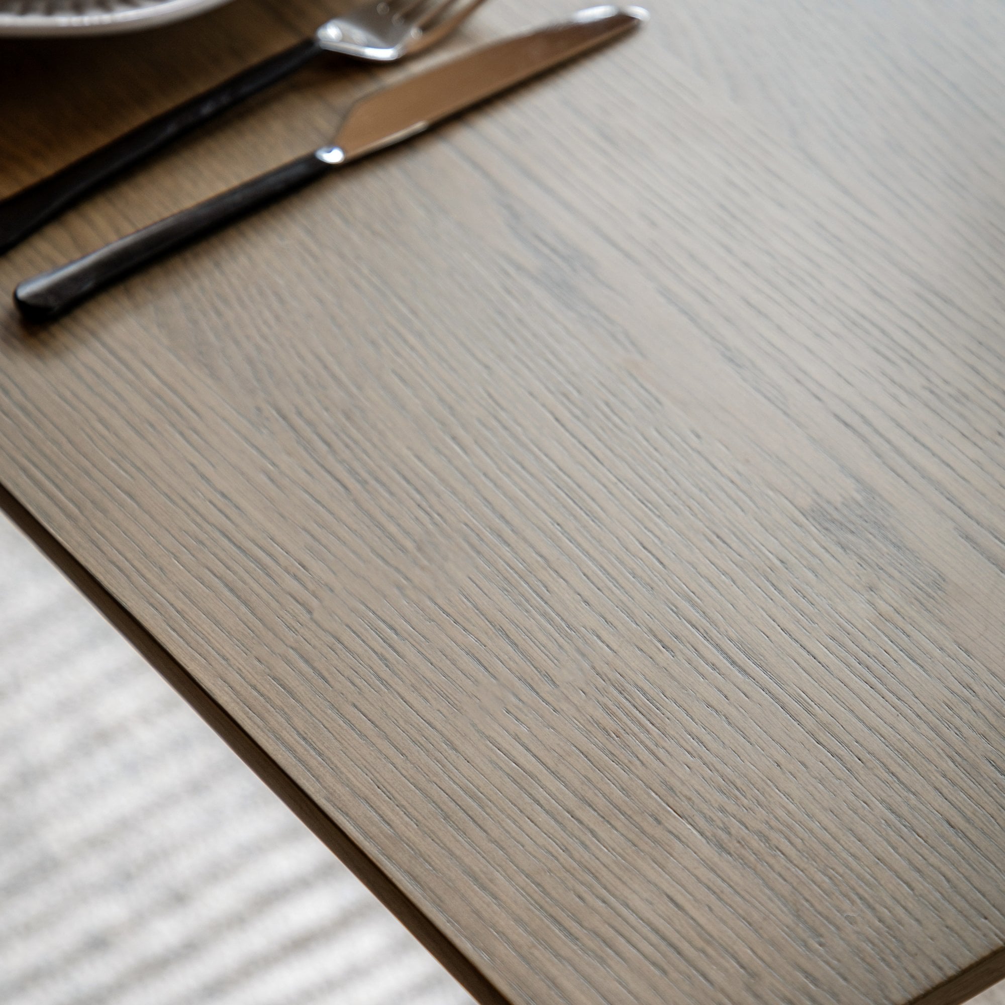 Detailed view of the wood grain on the tabletop, with cutlery in the corner.
